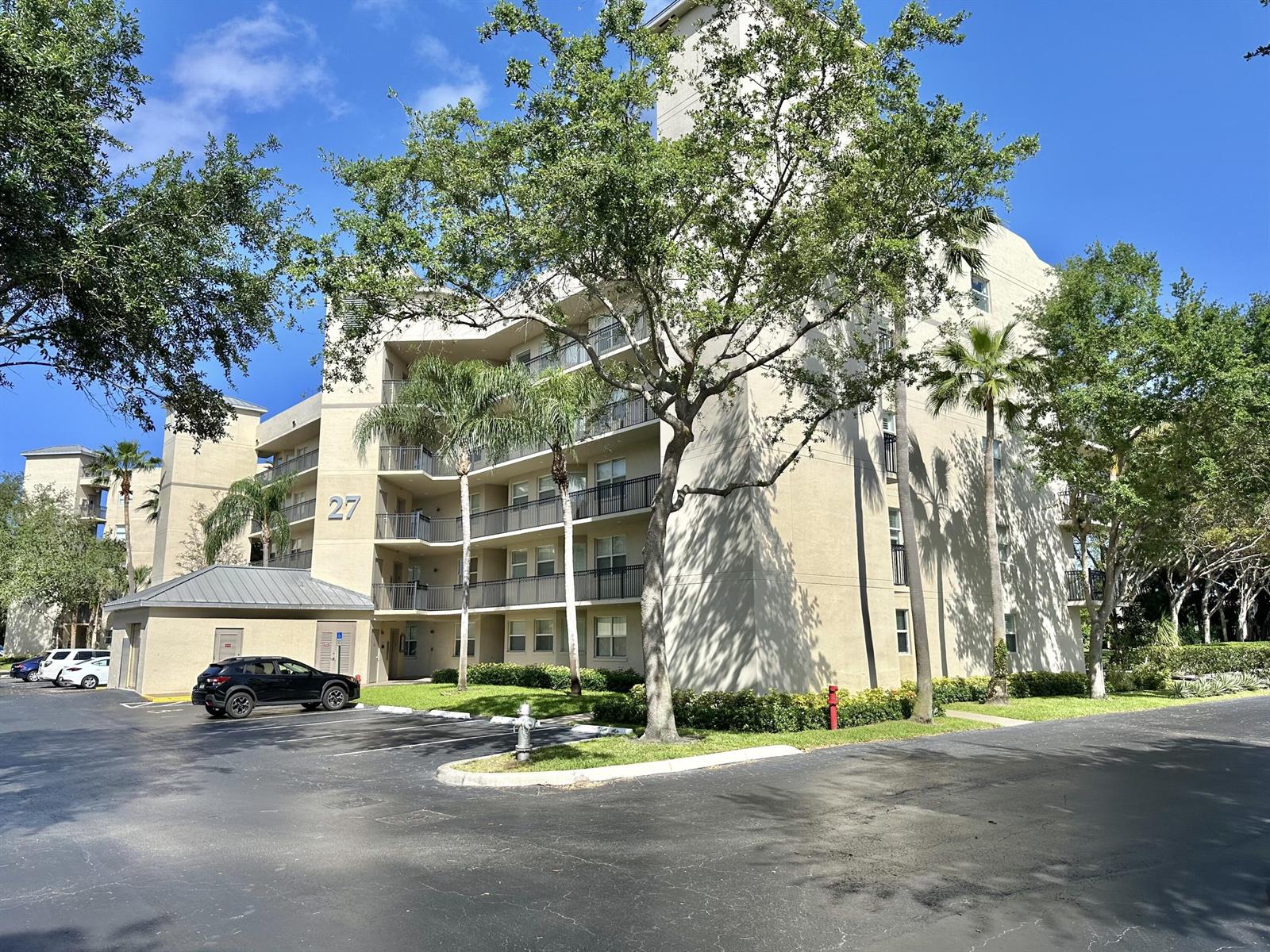 A multi-story apartment building with a parking lot and trees in front — 27 Royal Palm Way # 406, Boca Raton FL 33432, BOCA RATON, FL