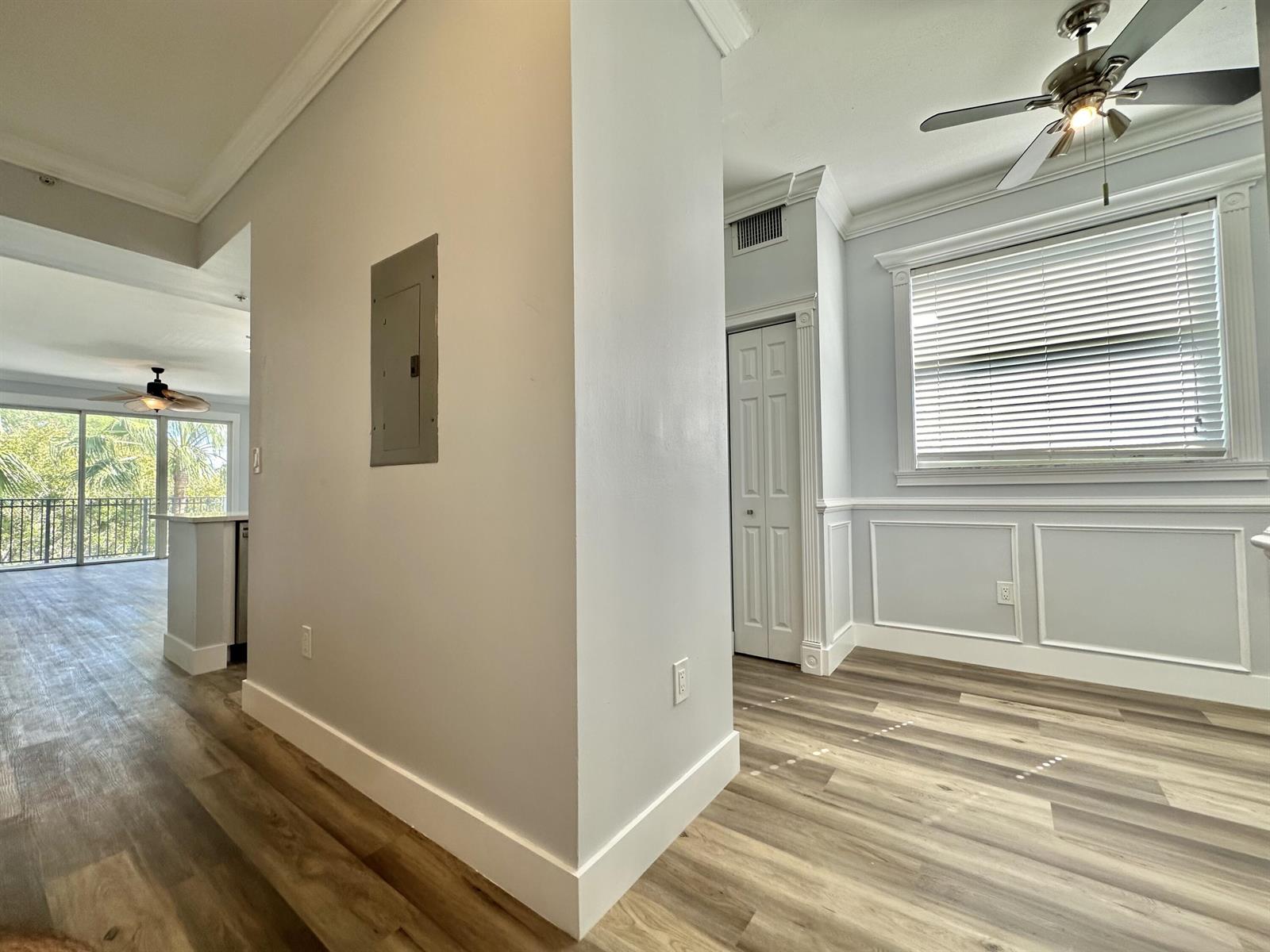 A room with light gray walls, white wainscoting, wood-look flooring, and a ceiling fan — 27 Royal Palm Way # 406, Boca Raton FL 33432, BOCA RATON, FL