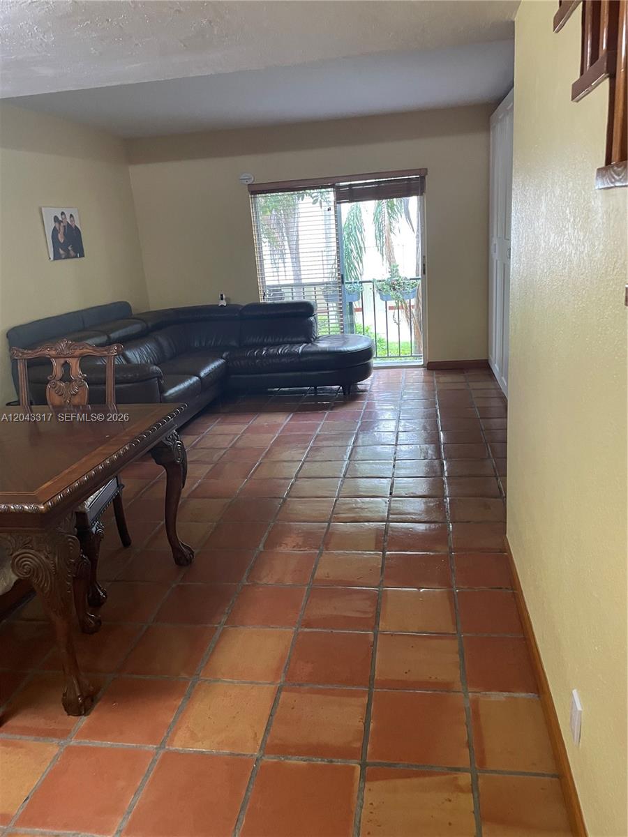 A living room features terracotta tile flooring, a black leather sectional, and a sliding glass door — 6705 N Kendall Dr # 312, Pinecrest FL 33156, PINECREST, FL