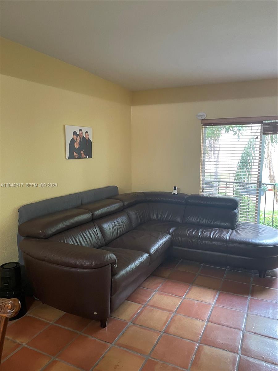A living room features a large brown leather sectional sofa on terracotta tile flooring — 6705 N Kendall Dr # 312, Pinecrest FL 33156, PINECREST, FL