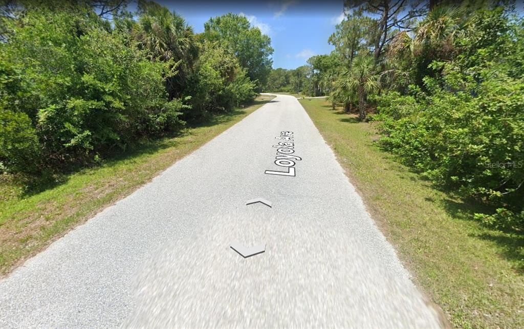 A paved road stretches through a wooded area with dense green trees and vegetation — 9366 LOYOLA AVENUE, ENGLEWOOD, FL