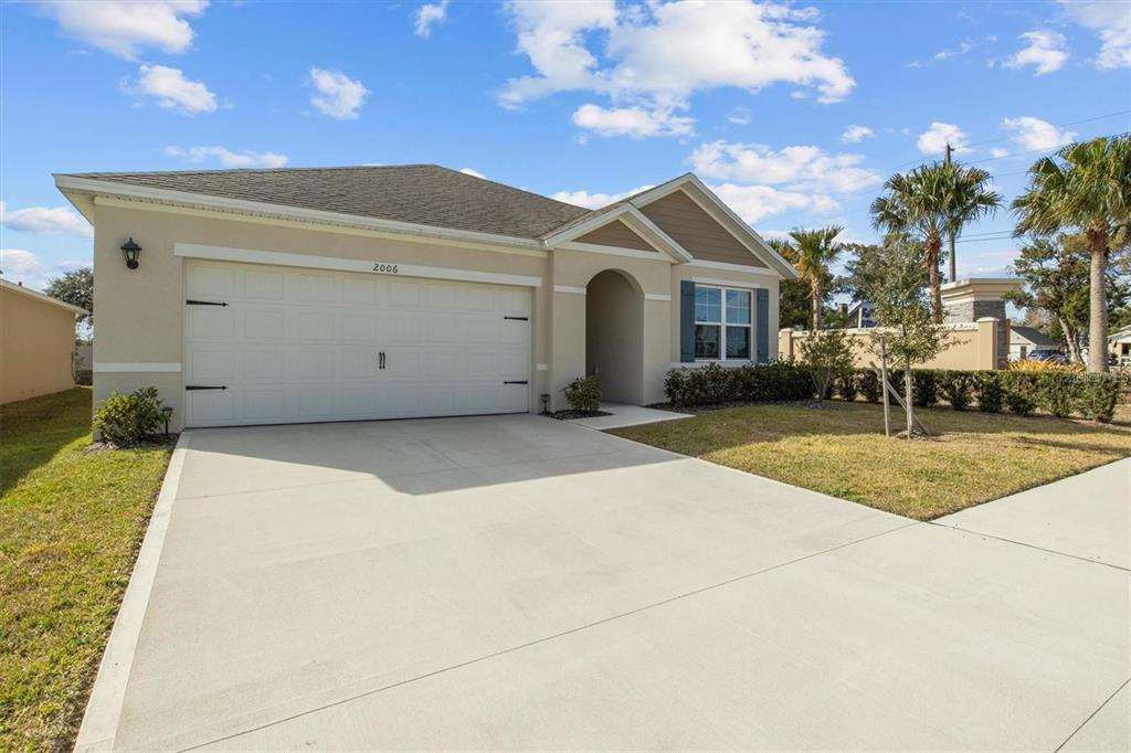 A single-story house with a beige stucco exterior, a two-car garage, and a concrete driveway — 2006 DOE RUN DRIVE, DAVENPORT, FL