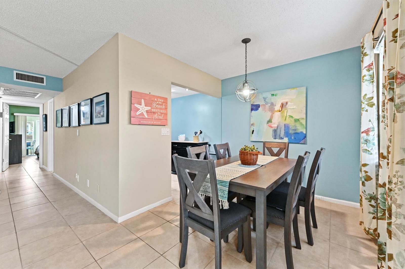 A dining room features a wooden table, six chairs, and a light blue accent wall — 196 Grantham F # 196, Deerfield Beach FL 33442, DEERFIELD BEACH, FL