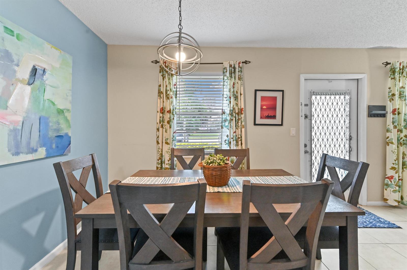 A dining room features a wooden table with x-back chairs under a spherical pendant light — 196 Grantham F # 196, Deerfield Beach FL 33442, DEERFIELD BEACH, FL