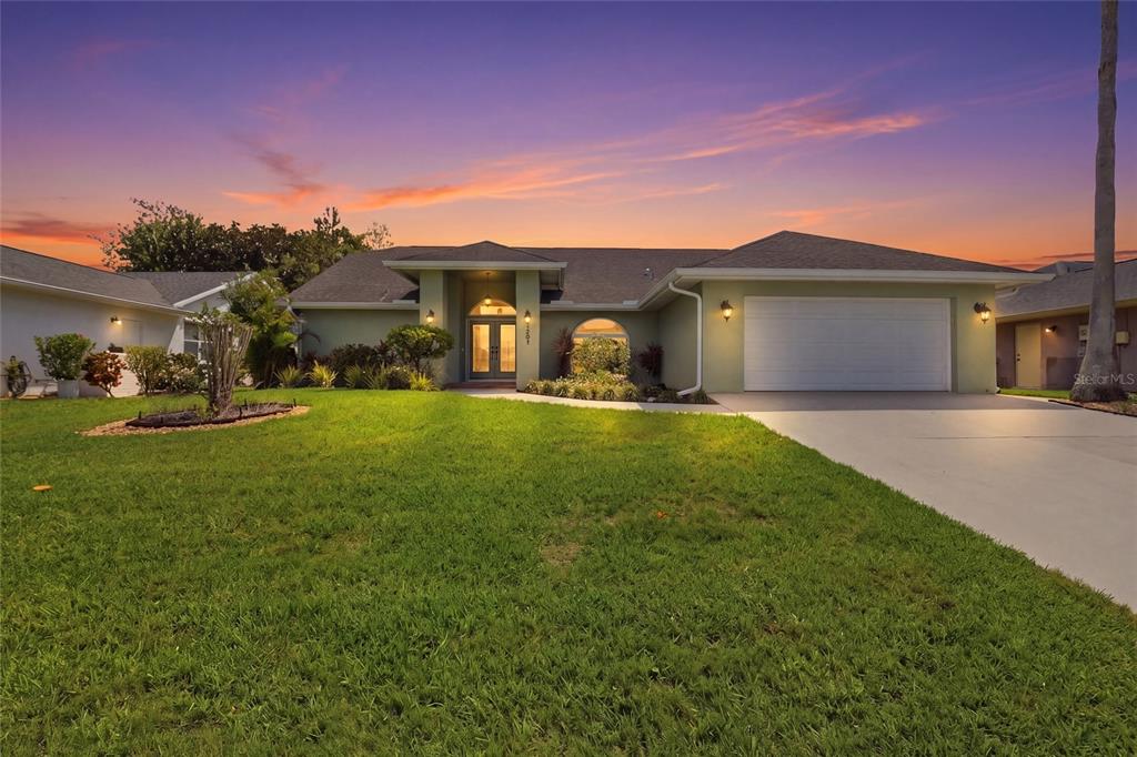 A single-story house with a green exterior, a two-car garage, and a landscaped front lawn — 5207 86TH STREET COURT W, BRADENTON, FL