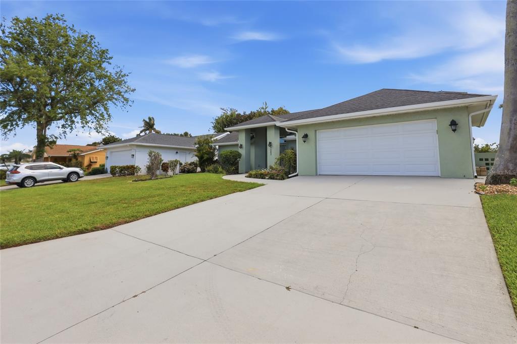 A light green house with a two-car garage and a concrete driveway — 5207 86TH STREET COURT W, BRADENTON, FL