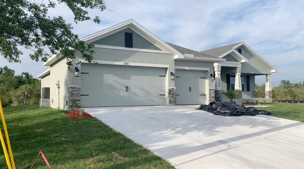 A single-story house with a three-car garage, stone accents, and a concrete driveway — 13236 PACE CIRCLE, PORT CHARLOTTE, FL