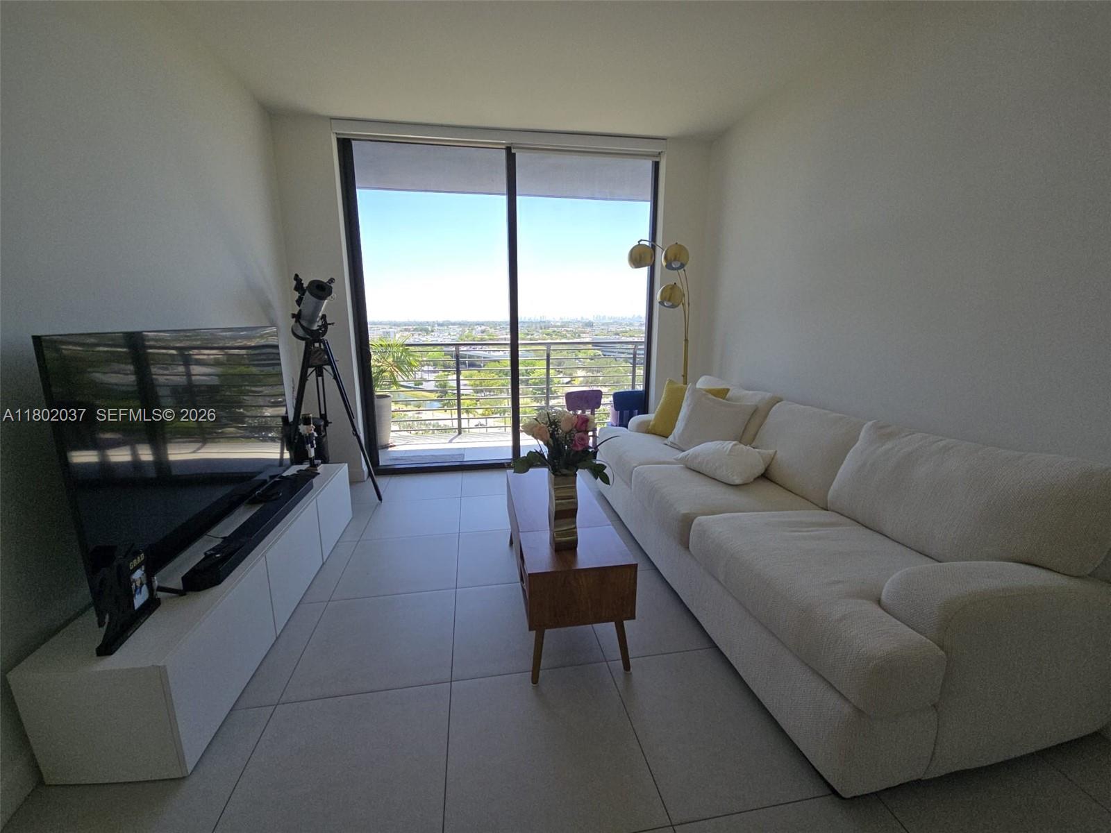 A living room features a white sofa, a television on a console, and a balcony view — 5350 NW 84th Ave # 1207, Doral FL 33166, DORAL, FL