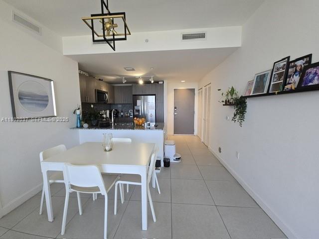 A modern dining area features a white table and chairs adjacent to an open kitchen — 5350 NW 84th Ave # 1207, Doral FL 33166, DORAL, FL