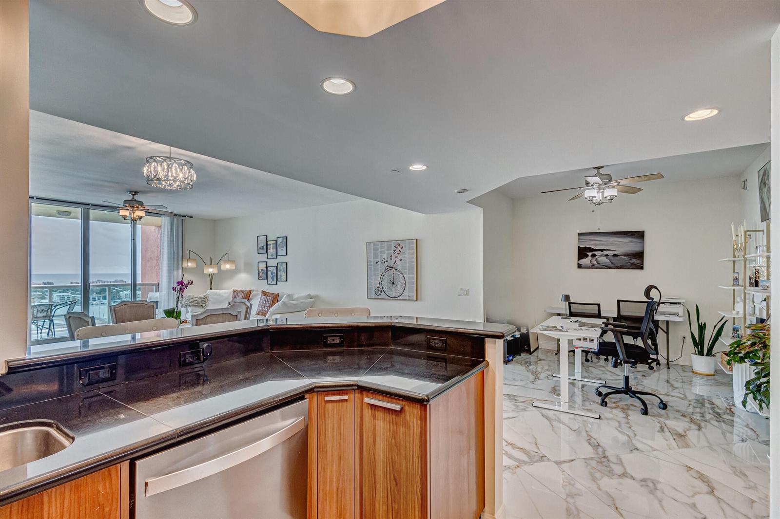 A kitchen counter overlooks a living area and a home office with marble-style flooring — 2640 Lake Shore Drive # 2014, Riviera Beach FL 33404, RIVIERA BEACH, FL