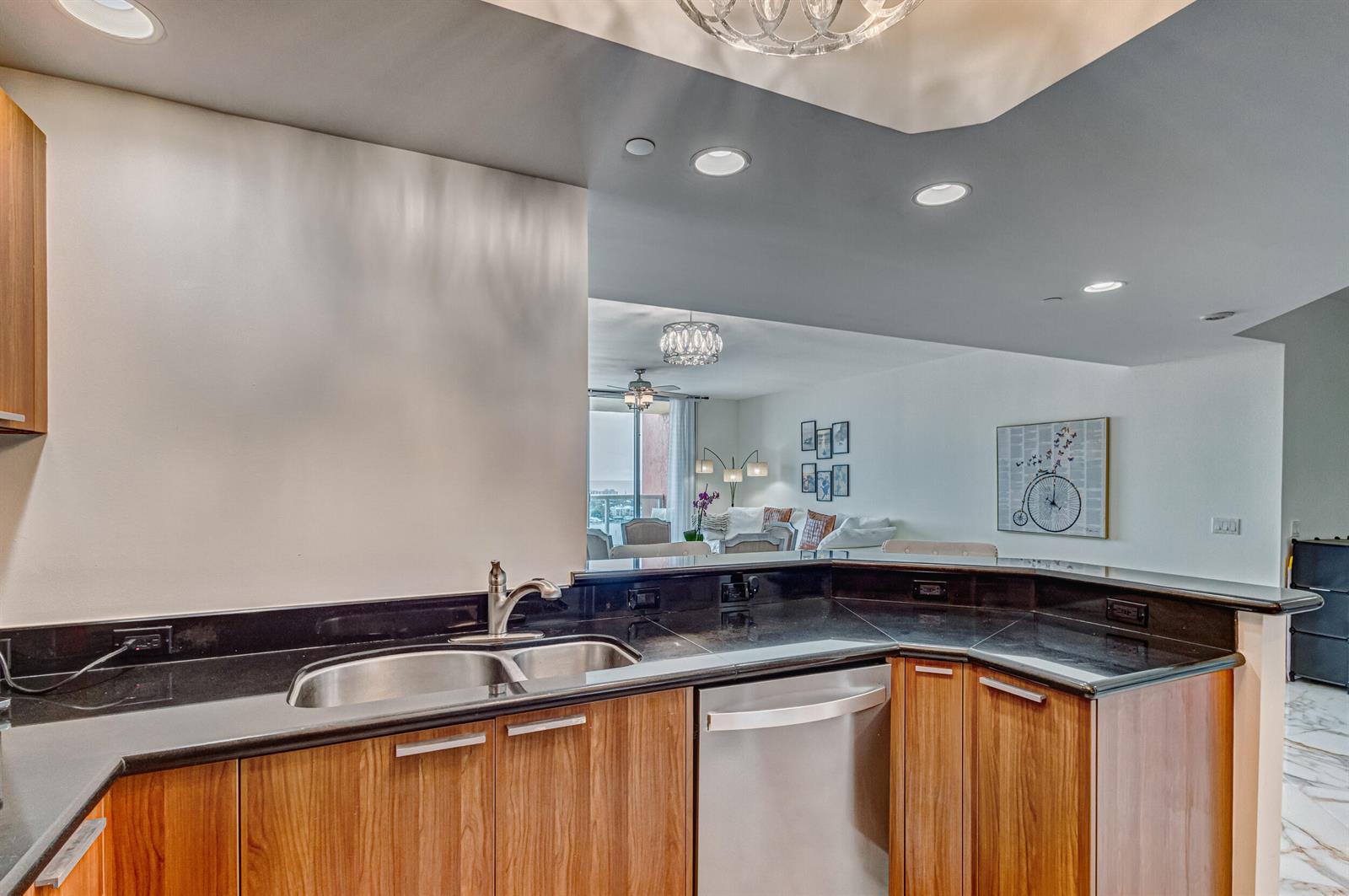 A kitchen features wood cabinets, black granite countertops, a stainless steel dishwasher, and recessed lighting — 2640 Lake Shore Drive # 2014, Riviera Beach FL 33404, RIVIERA BEACH, FL