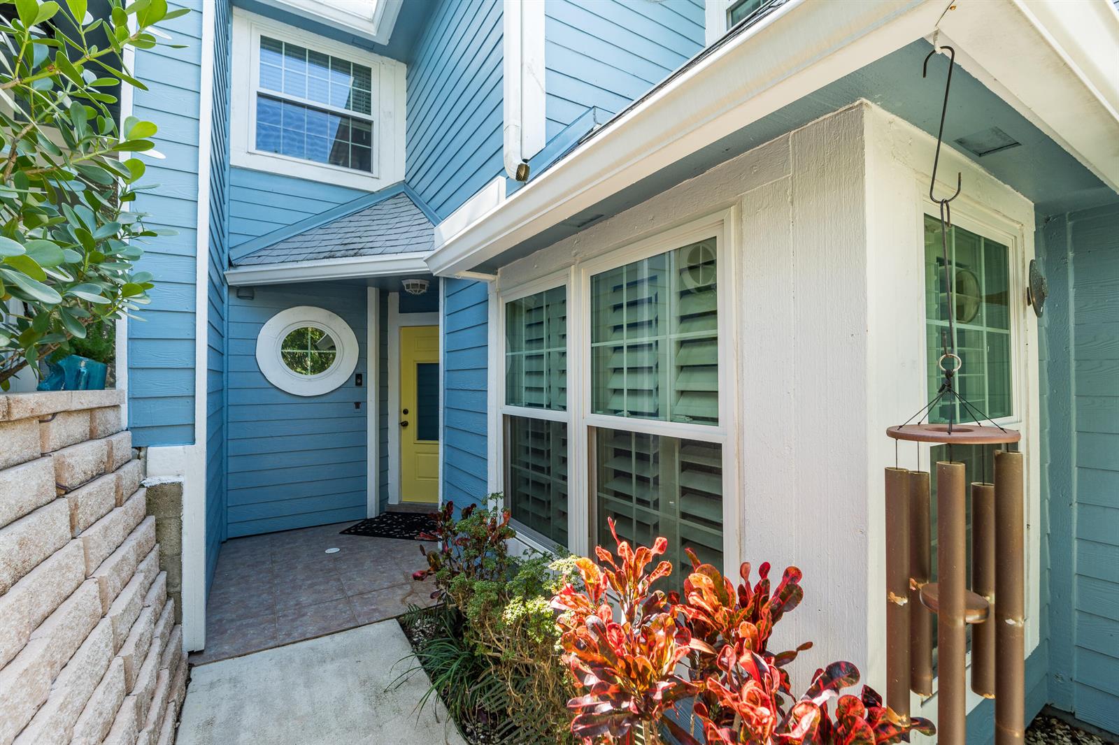 A blue house exterior features a yellow front door, a round window, and a small porch — 127 Ocean Dunes Circle, Jupiter FL 33477, JUPITER, FL