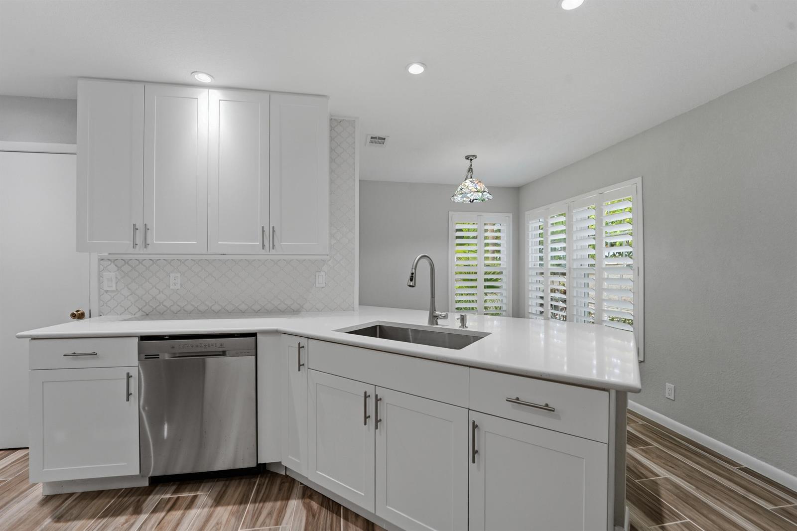 A kitchen features white cabinets, a stainless steel dishwasher, a sink, and tiled flooring — 127 Ocean Dunes Circle, Jupiter FL 33477, JUPITER, FL