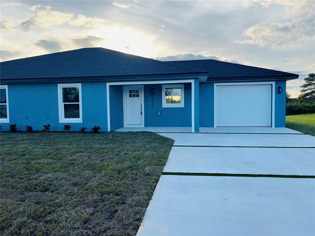 A blue, single-story house with a white front door, garage, and concrete driveway — 6801 DICKINSON DRIVE, SEBRING, FL