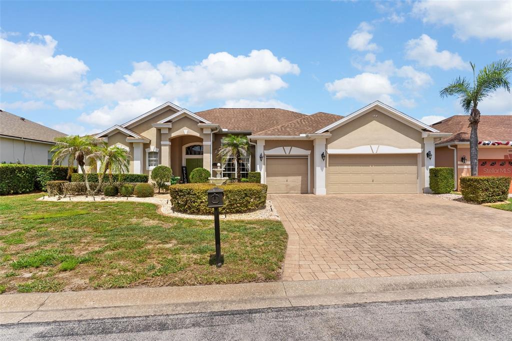 A single-story house with a tan stucco exterior, a paved driveway, and a three-car garage — 622 GOLF COURSE PARKWAY, DAVENPORT, FL