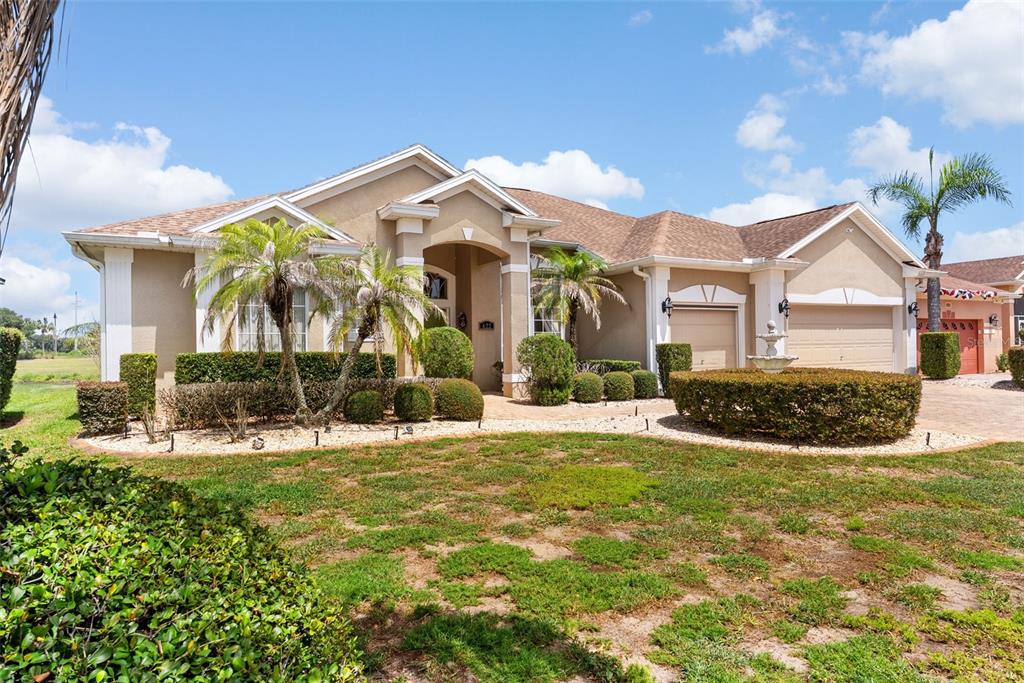 A tan, single-story suburban house with a multi-car garage and a front yard fountain — 622 GOLF COURSE PARKWAY, DAVENPORT, FL