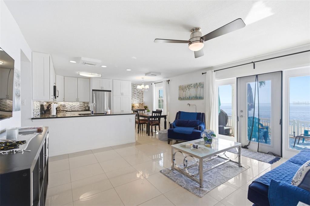 An open-concept kitchen and living area features white cabinetry, tile flooring, and a waterfront view — 5280 COQUINA KEY DRIVE SE UNIT A furnished seasonal, ST PETERSBURG, FL