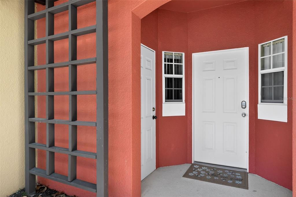 A front entryway features a white door, a side door, and a wooden trellis — 8538 CRYSTAL COVE LOOP, KISSIMMEE, FL