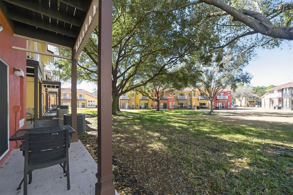 A view from a covered patio looking out onto a grassy courtyard and apartment buildings — 8538 CRYSTAL COVE LOOP, KISSIMMEE, FL