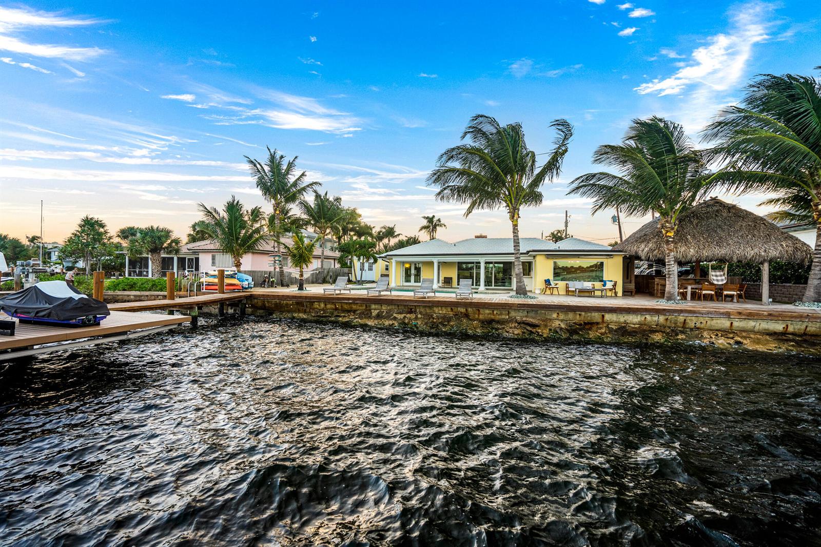 A yellow waterfront house with a dock, palm trees, and a thatched-roof tiki hut — 844 East Drive, Boynton Beach FL 33435, BOYNTON BEACH, FL