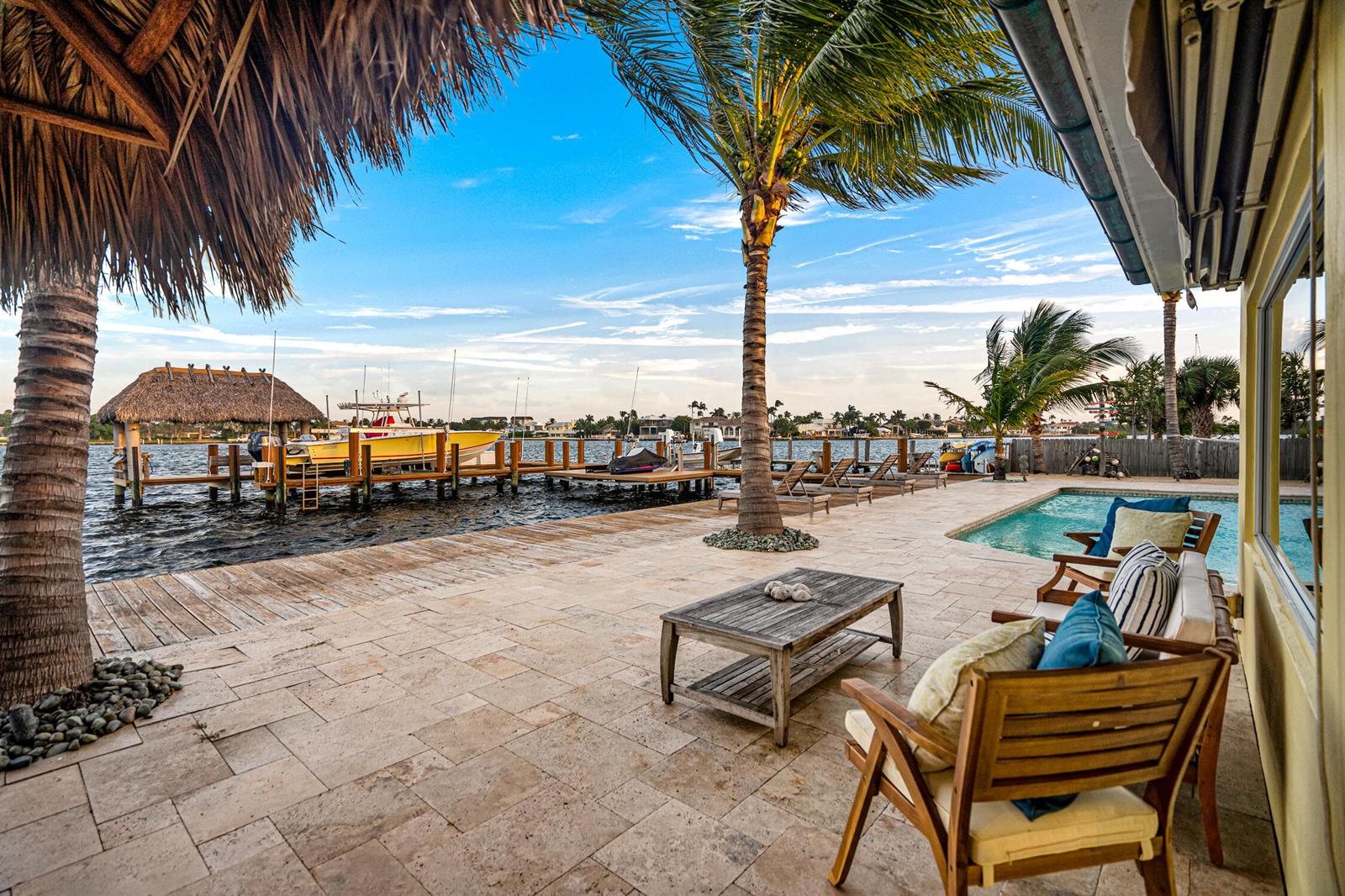 A patio with a pool and wooden furniture overlooks a boat dock on the water — 844 East Drive, Boynton Beach FL 33435, BOYNTON BEACH, FL