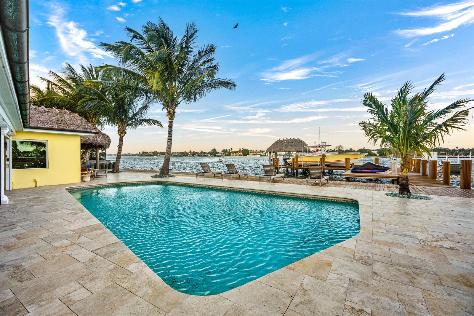 A swimming pool sits on a stone patio next to a dock with a boat — 844 East Drive, Boynton Beach FL 33435, BOYNTON BEACH, FL