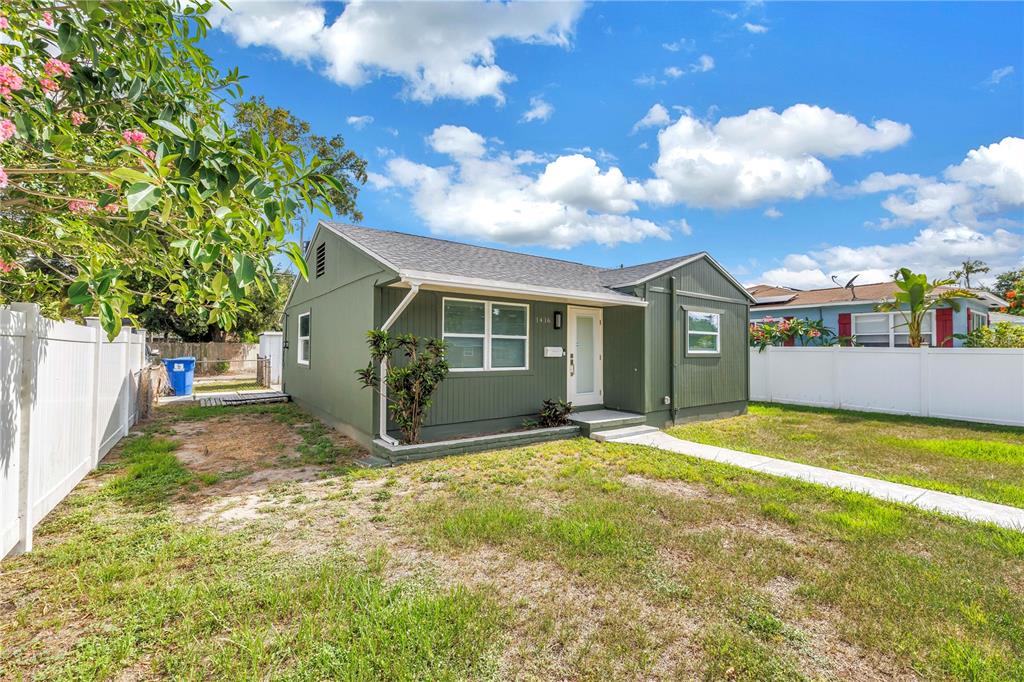 A green single-story house with a white fence and a concrete walkway in the yard — 1416 38TH AVENUE N, ST PETERSBURG, FL