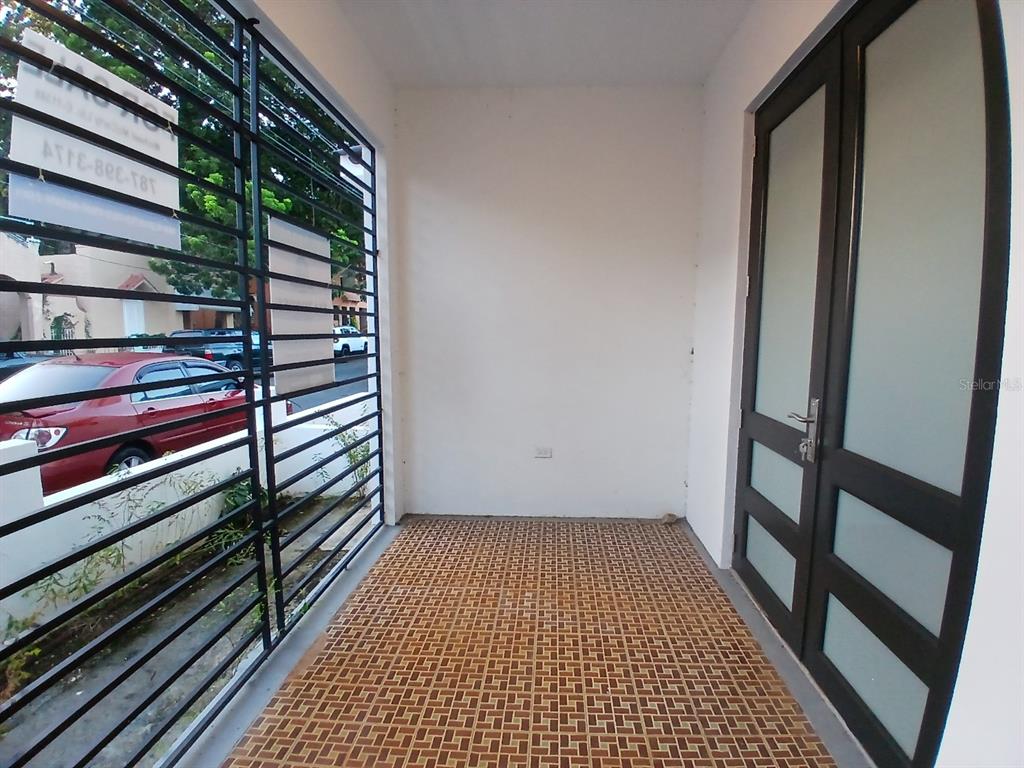 A covered porch with tiled flooring, a metal security gate, and a glass-paneled door — 1002 MADRID STREET, SAN JUAN, PR