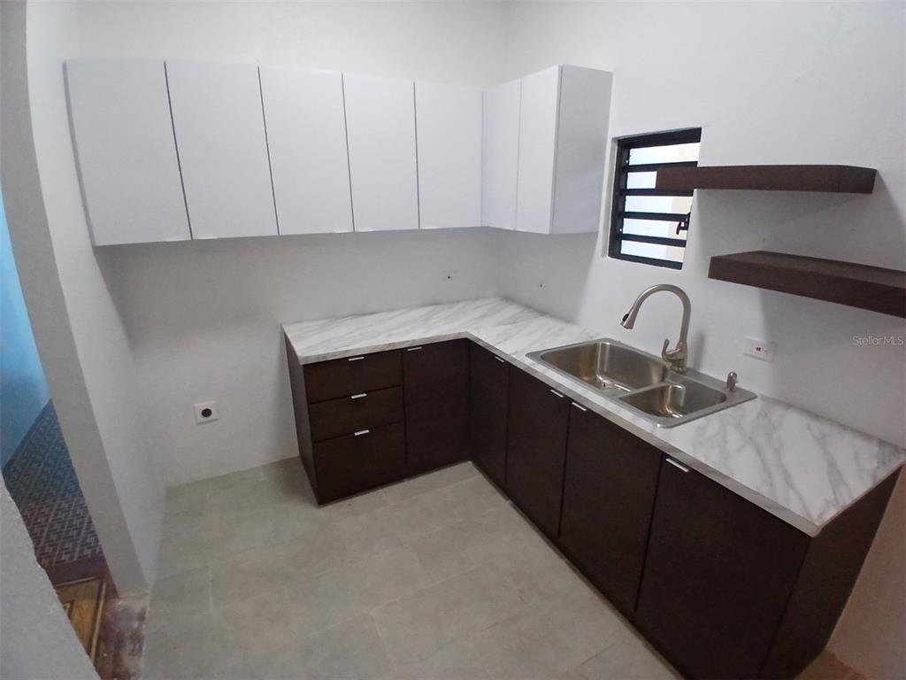 A kitchen features white upper cabinets, dark lower cabinets, marble-look countertops, and open wooden shelving — 1002 MADRID STREET, SAN JUAN, PR