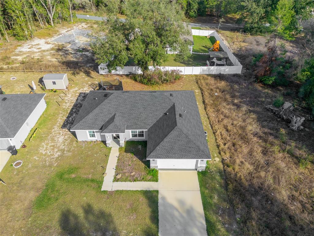 An aerial view shows a single-story house with a dark shingled roof and concrete driveway — 1780 SW 168TH LOOP, OCALA, FL