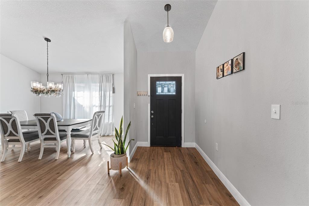 A foyer with wood-look flooring leads to a dining area with a chandelier and curtains — 1780 SW 168TH LOOP, OCALA, FL
