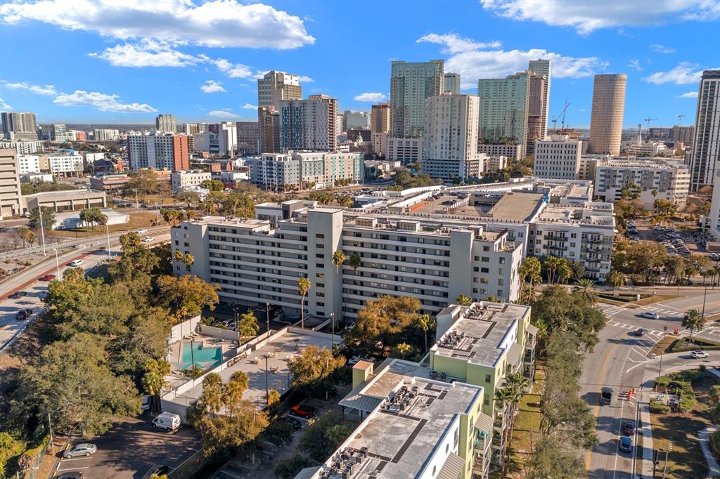 An aerial view shows a large apartment complex with a pool and surrounding city skyline — 201 W LAUREL STREET UNIT 310, TAMPA, FL