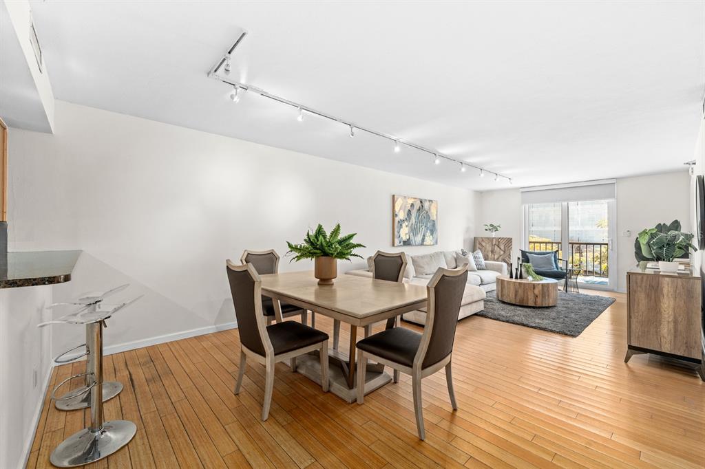An open-concept living and dining area features hardwood floors, track lighting, and a balcony view — 201 W LAUREL STREET UNIT 310, TAMPA, FL