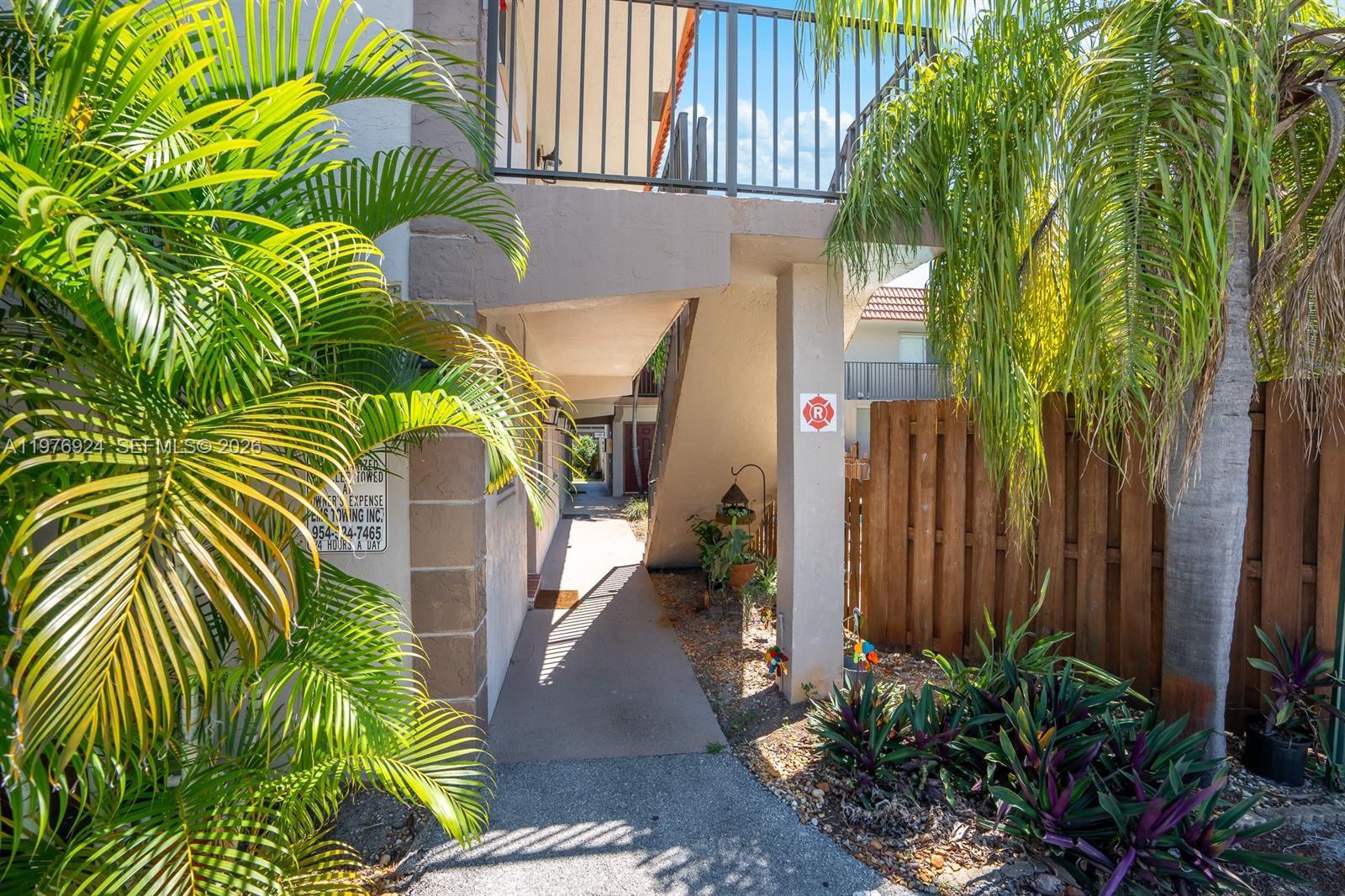A concrete walkway leads under an outdoor staircase between a building and a wooden fence — 3050 NE 5th Ter # 8, Wilton Manors FL 33334, WILTON MANORS, FL