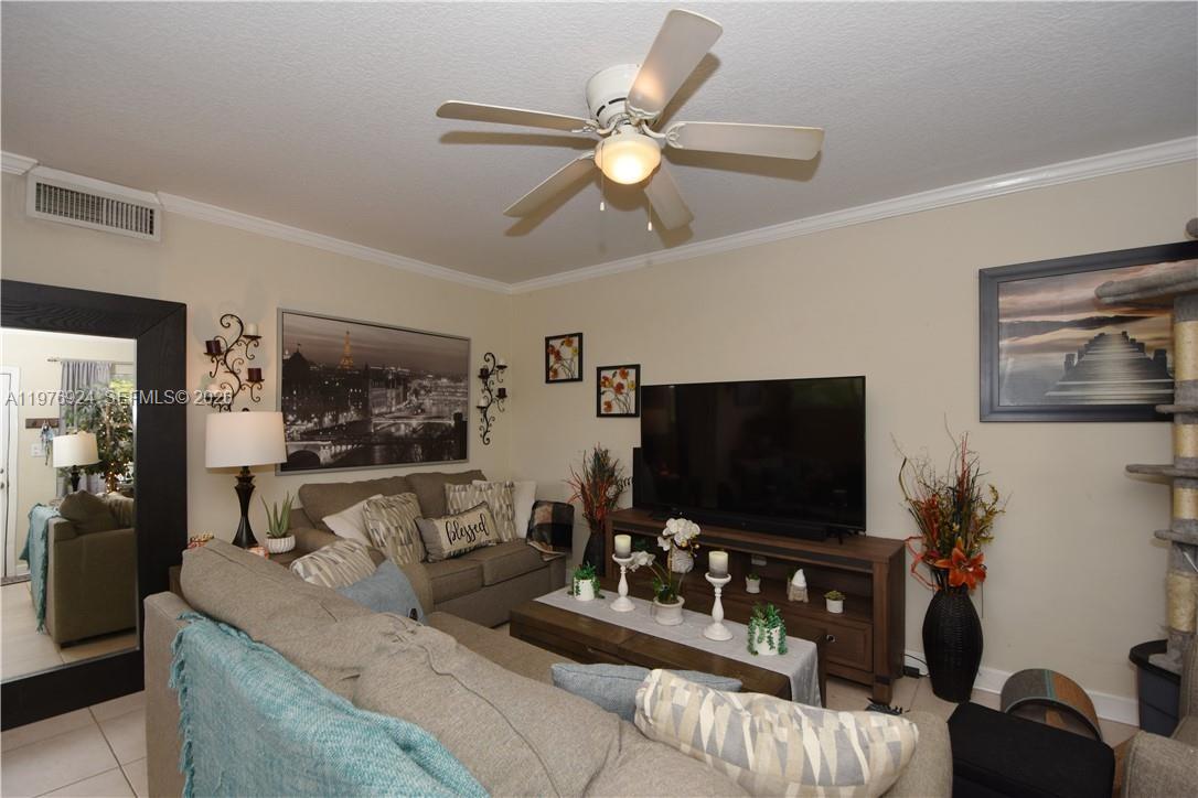 A living room features a sectional sofa, a television on a console, and a ceiling fan — 3050 NE 5th Ter # 8, Wilton Manors FL 33334, WILTON MANORS, FL