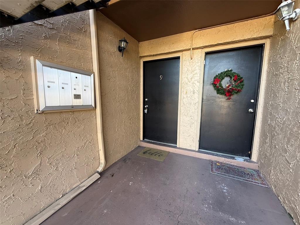 An exterior view of two black apartment doors with a wall-mounted mailbox unit — 1575 GREENLEA DRIVE UNIT 9, CLEARWATER, FL