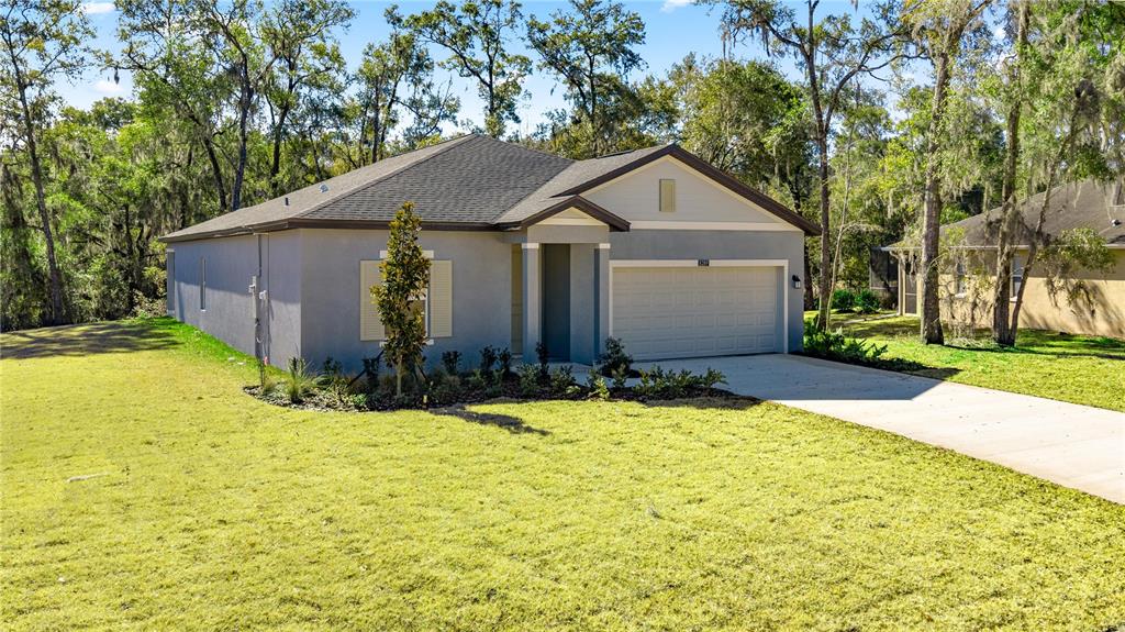 A single-story house with a gray stucco exterior, a two-car garage, and a grassy yard — 8363 SW 197TH COURT, DUNNELLON, FL