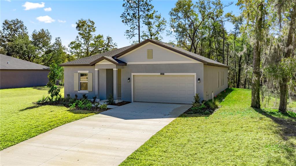 A single-story house with a gray stucco exterior, a two-car garage, and a concrete driveway — 8363 SW 197TH COURT, DUNNELLON, FL