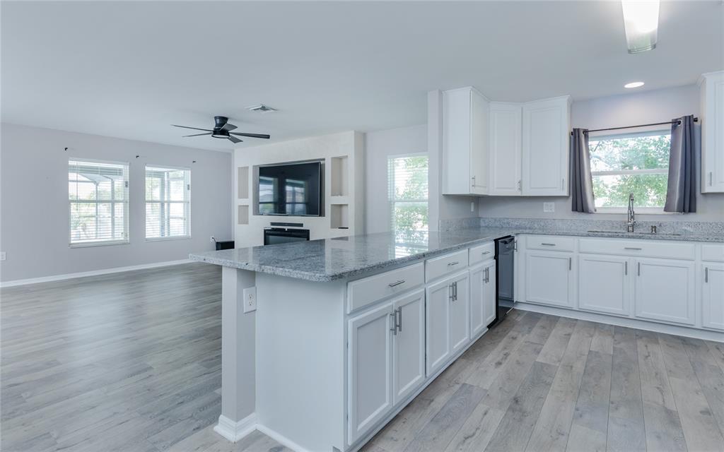 A kitchen with white cabinets and granite countertops opens into a living area with flooring — 1916 SW 12TH TERRACE, CAPE CORAL, FL