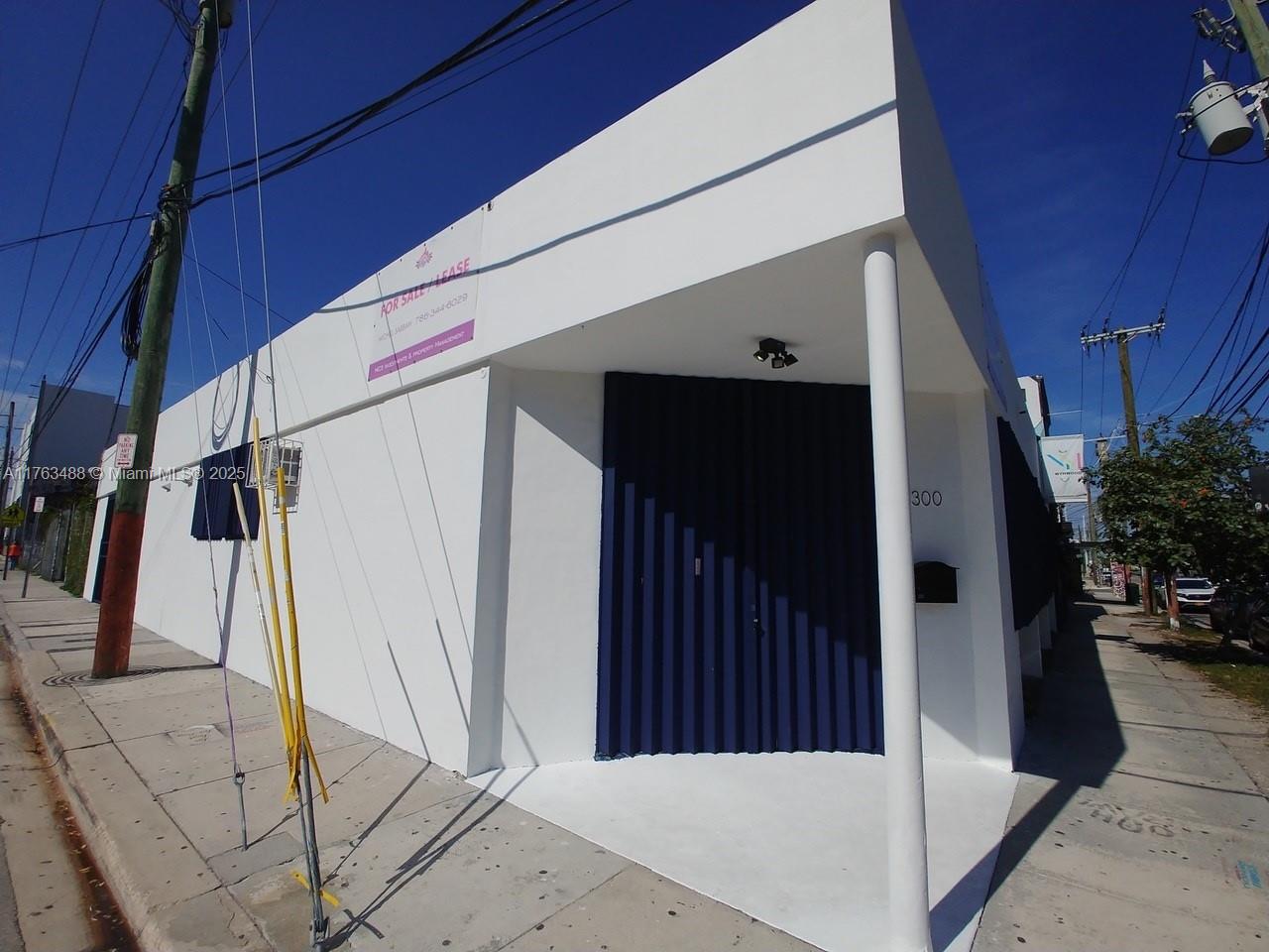 A white commercial building with a blue accordion door and a corner entrance — 2300 N Miami Ave, Miami FL 33127, MIAMI, FL