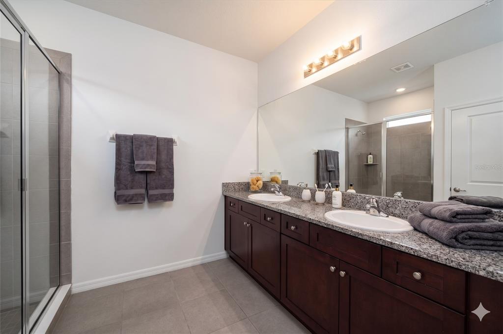 A bathroom features a double vanity with dark wood cabinets, granite countertops, and a glass shower — 9139 SW 60TH COURT ROAD, OCALA, FL