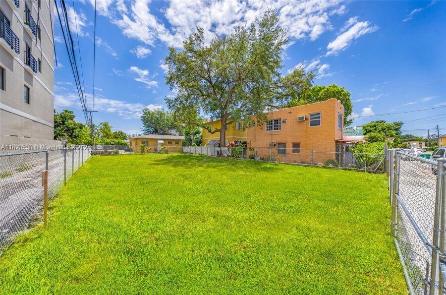 A grassy vacant lot sits between a modern apartment building and a two-story orange house — 129 SW 21st Ave, Miami FL 33135, MIAMI, FL