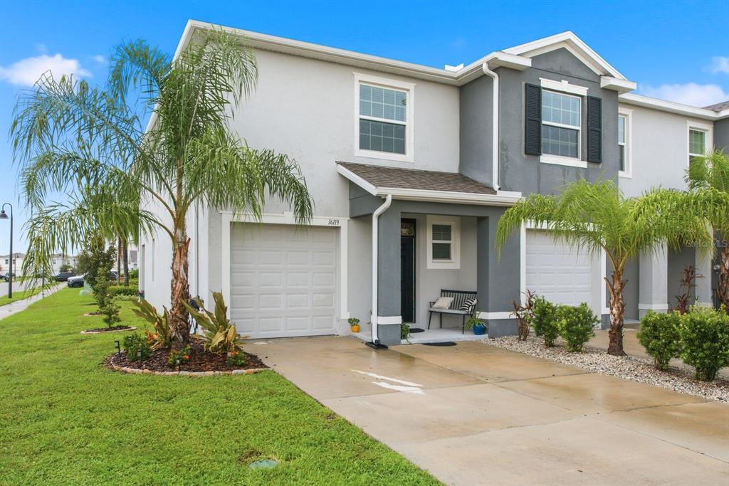 A two-story townhouse with a gray and white exterior, a garage, and a palm tree — 16119 GLOWING GROVE AVENUE, ODESSA, FL