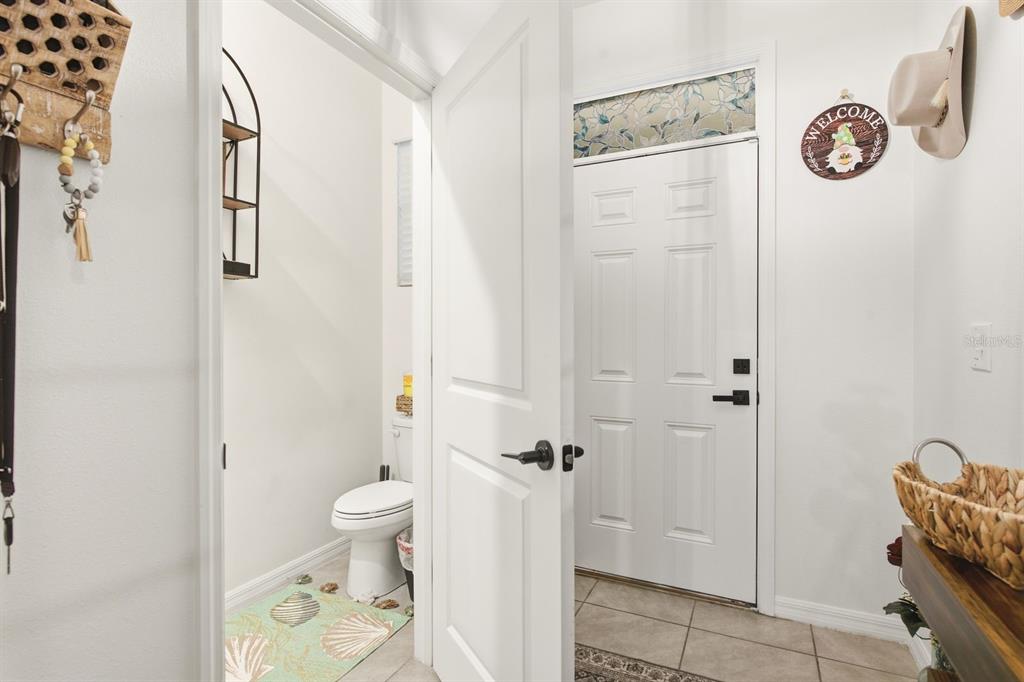 A small bathroom with a toilet is visible through an open doorway near an entryway — 16119 GLOWING GROVE AVENUE, ODESSA, FL