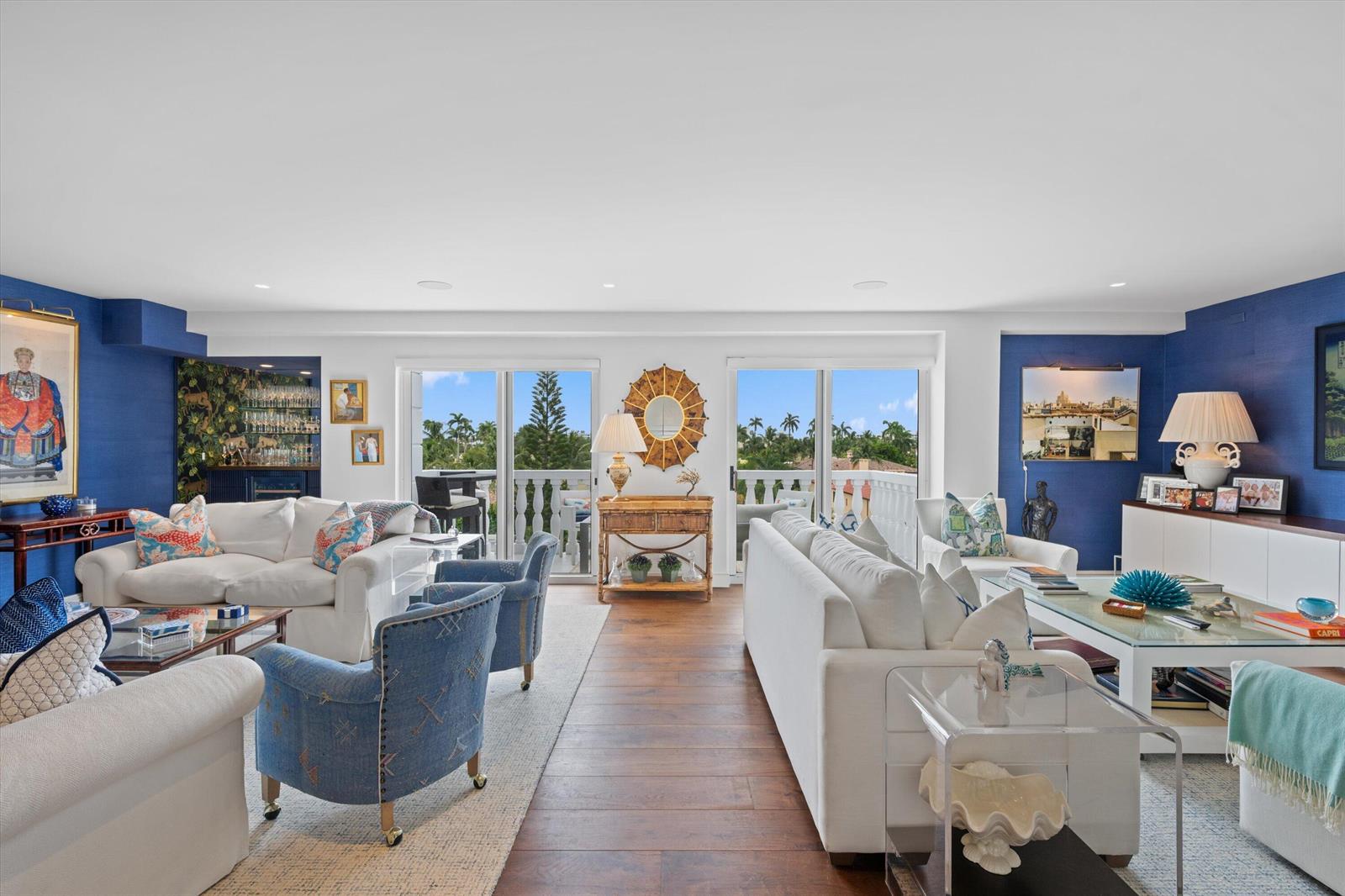 A spacious living room features white sofas, blue accent walls, and sliding glass balcony doors — 330 Cocoanut Row # 5b, Palm Beach FL 33480, PALM BEACH, FL