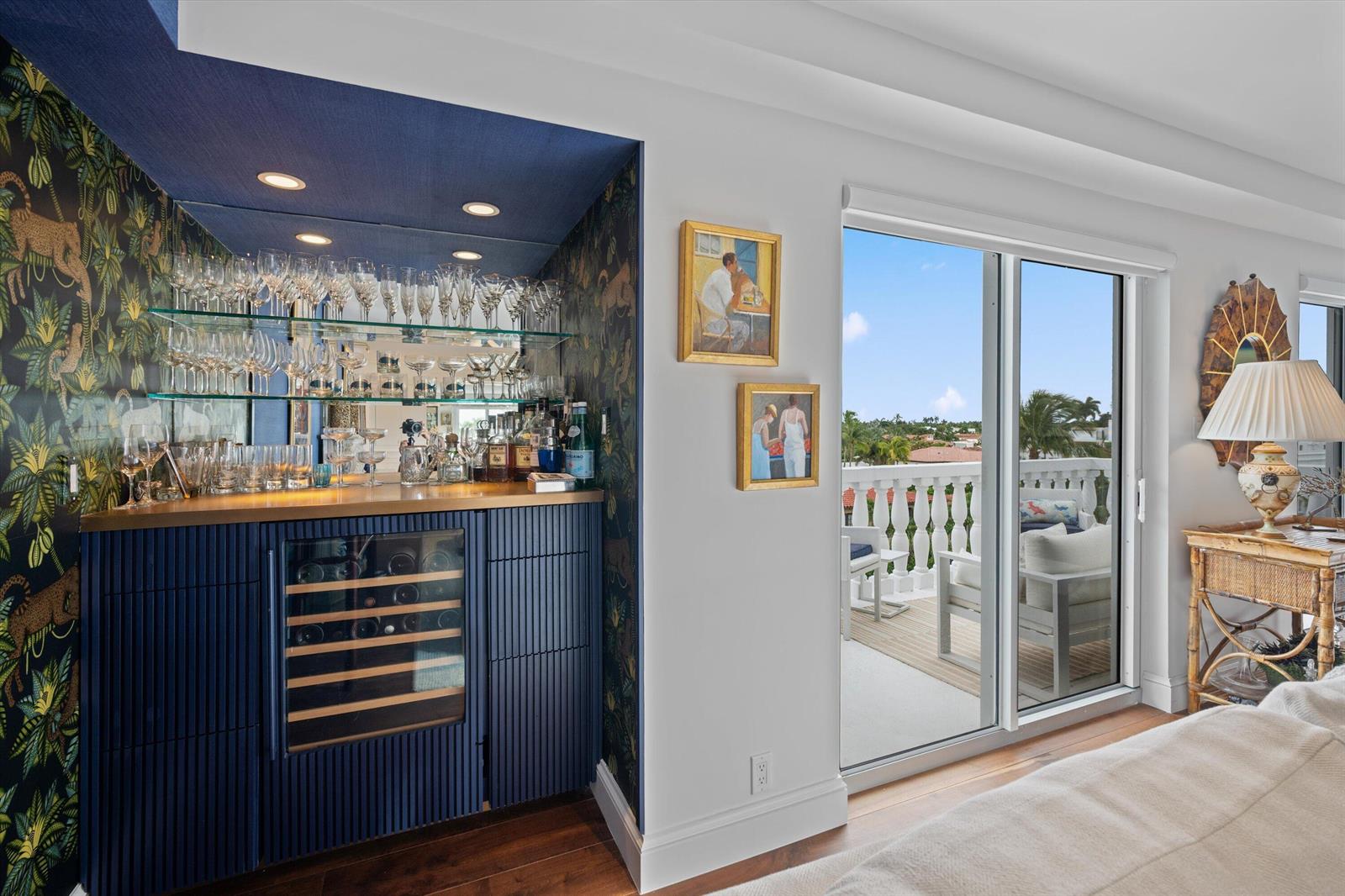 A bedroom features a built-in blue bar with glass shelving, wallpaper, and a balcony view — 330 Cocoanut Row # 5b, Palm Beach FL 33480, PALM BEACH, FL
