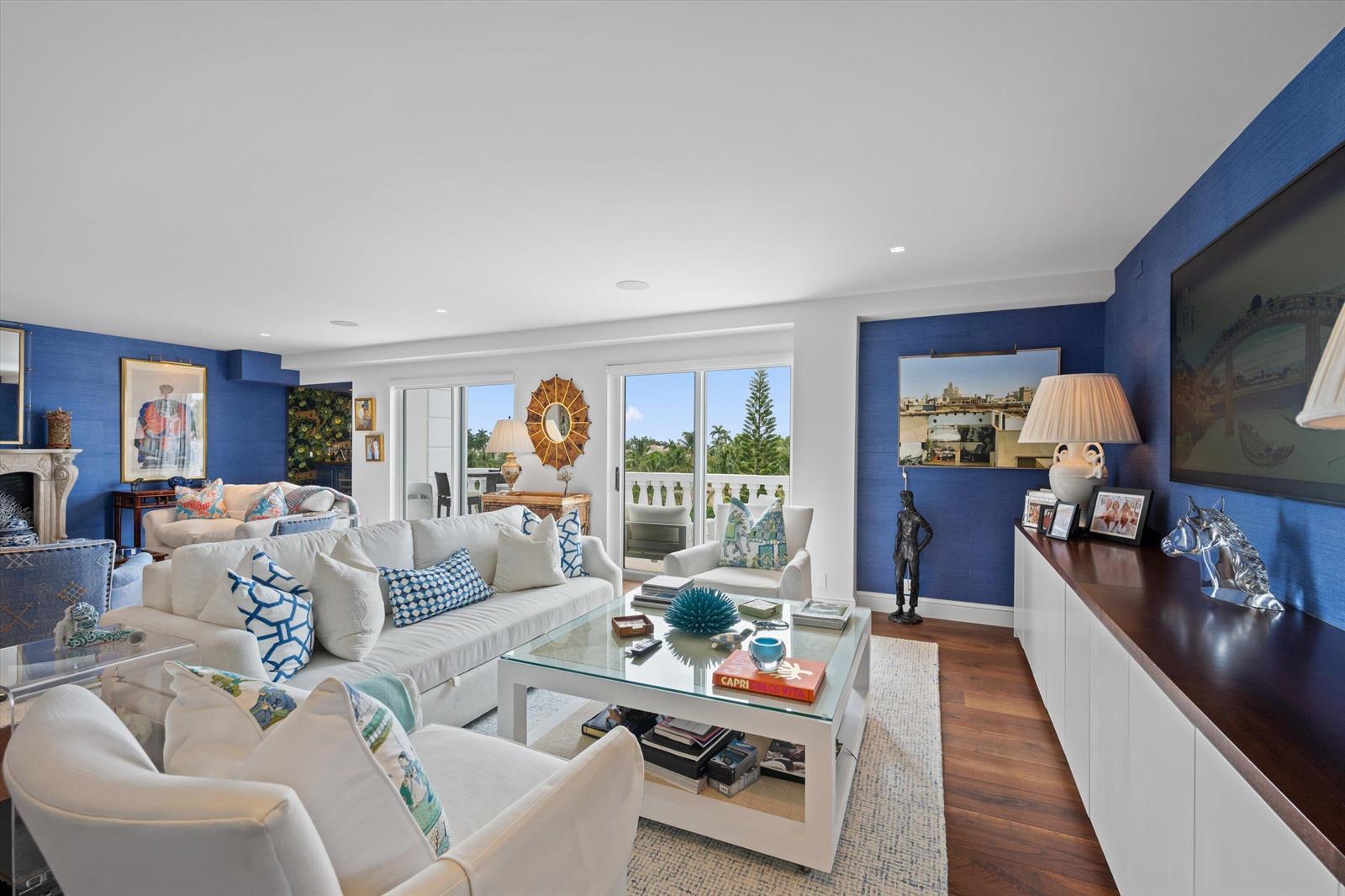 A bright living room features blue textured walls, white sofas, and a glass coffee table — 330 Cocoanut Row # 5b, Palm Beach FL 33480, PALM BEACH, FL