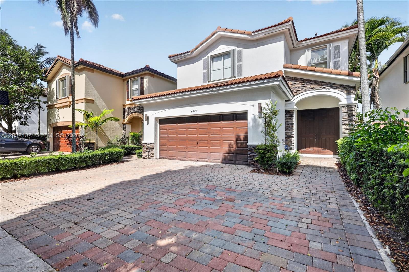 A two-story house features a paved driveway, a two-car garage, and a stone-accented exterior — 4422 NW 112th Ct, Doral FL 33178, DORAL, FL