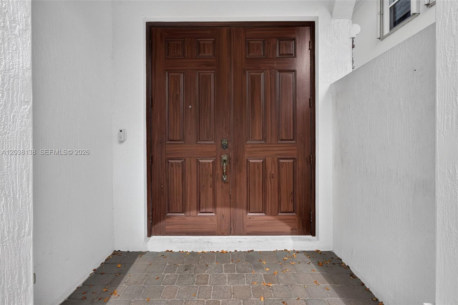 A set of double wooden doors is centered within a white-walled entryway with pavers — 4422 NW 112th Ct, Doral FL 33178, DORAL, FL