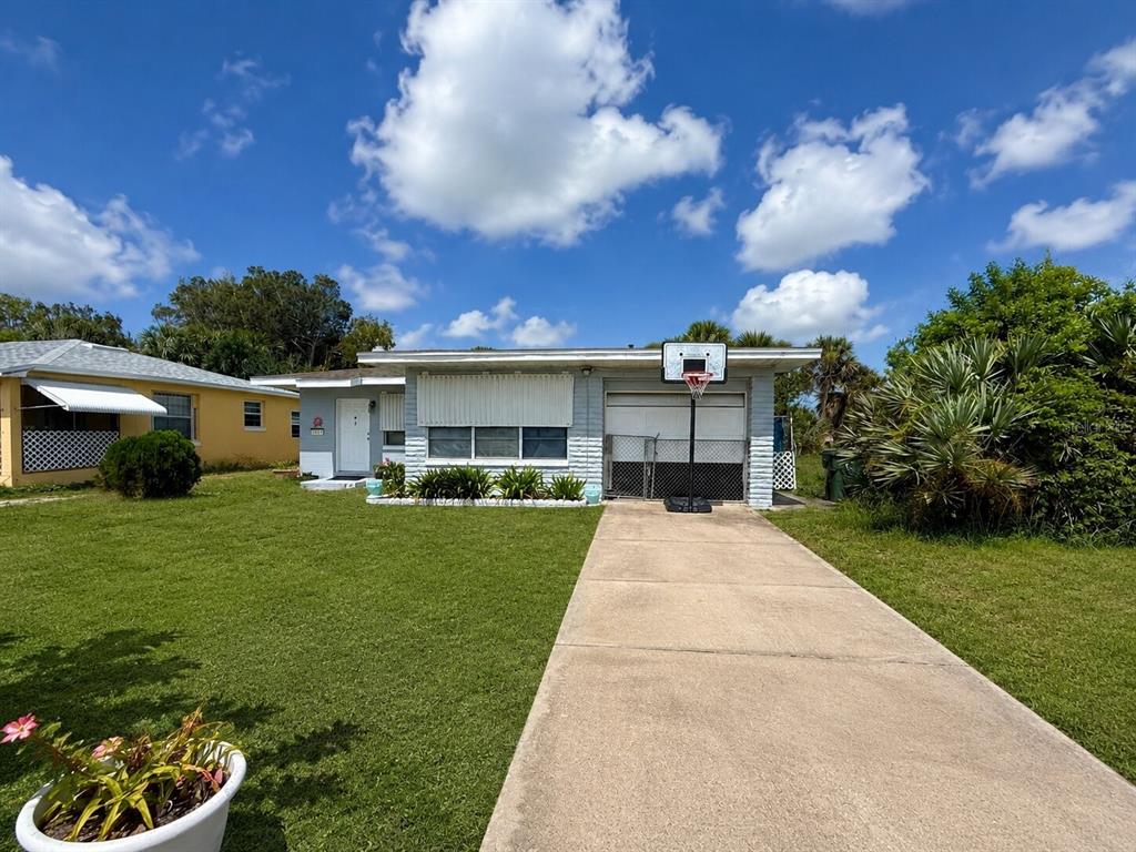 A single-story light blue house with a concrete driveway and a basketball hoop — 1517 N GRANDVIEW AVENUE, DAYTONA BEACH, FL